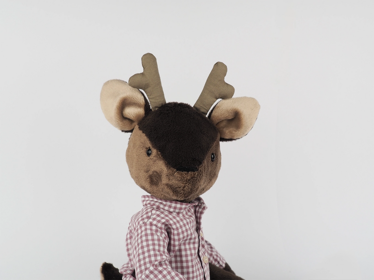 Deer doll wearing a checkered shirt on a light gray background