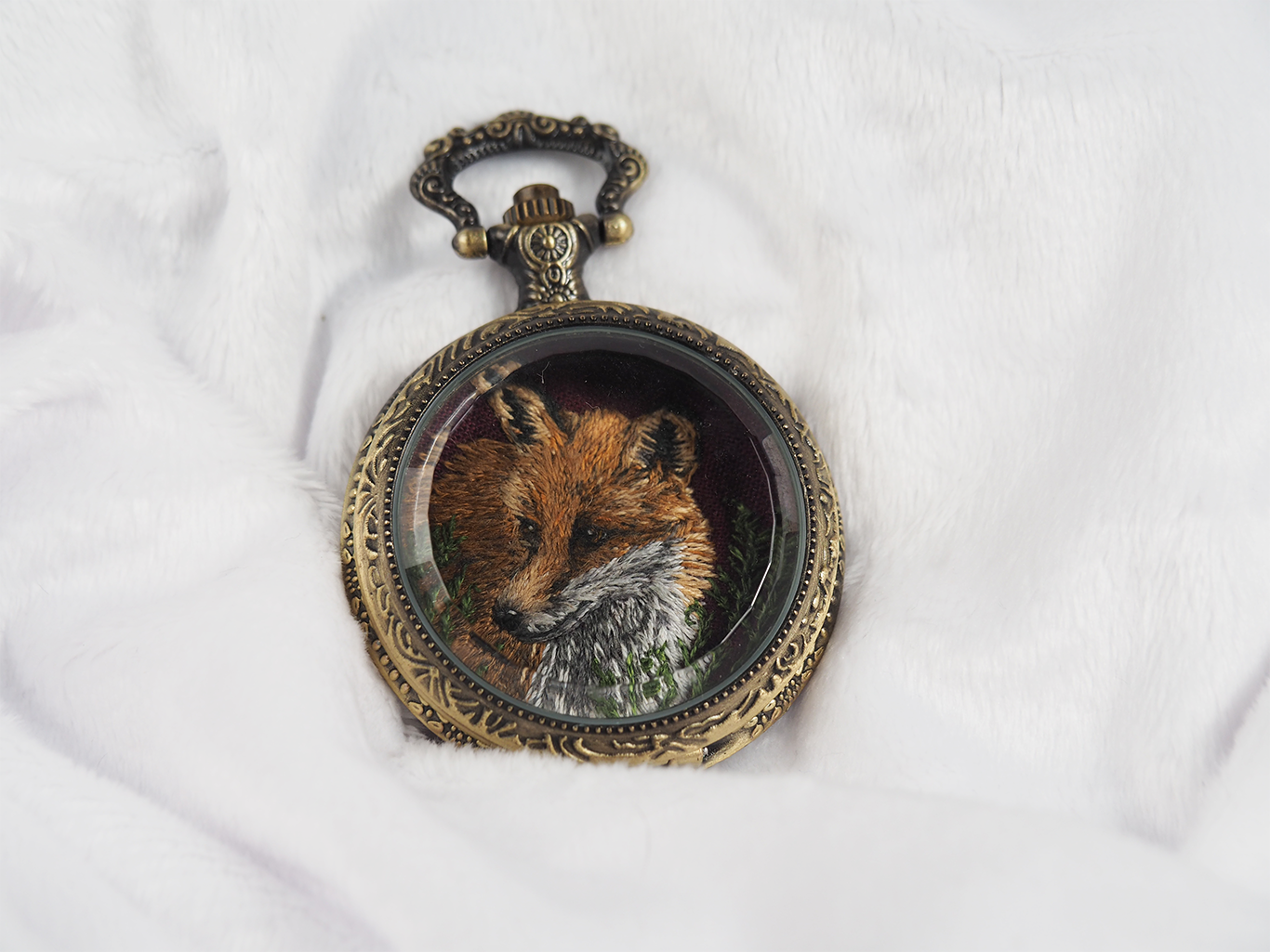 Closed locket casing with fox embroidery hidden inside.