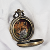 Side view of open locket showing embroidered fox.
