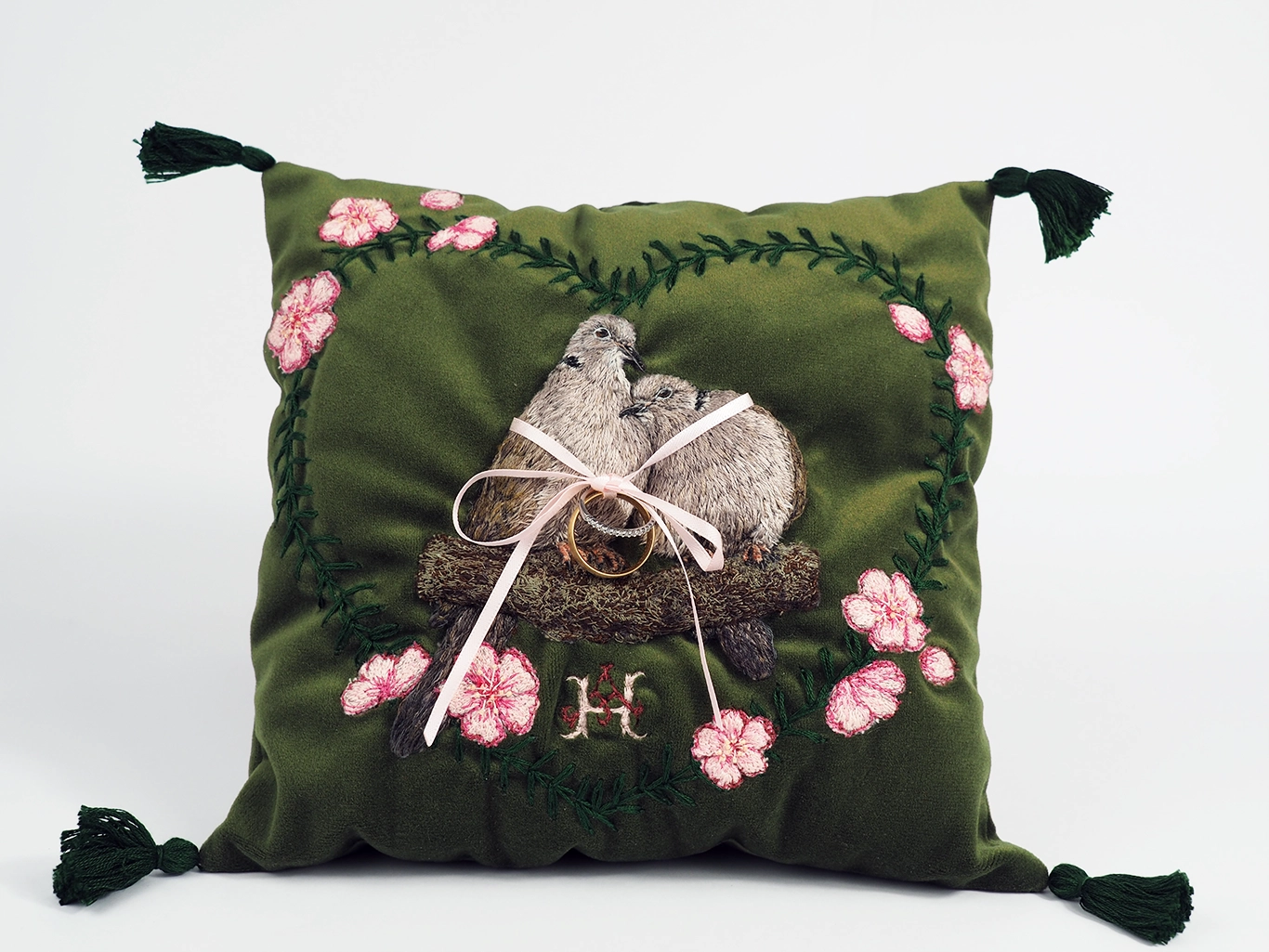 Decorative pillow with embroidered doves and flowers on a green background