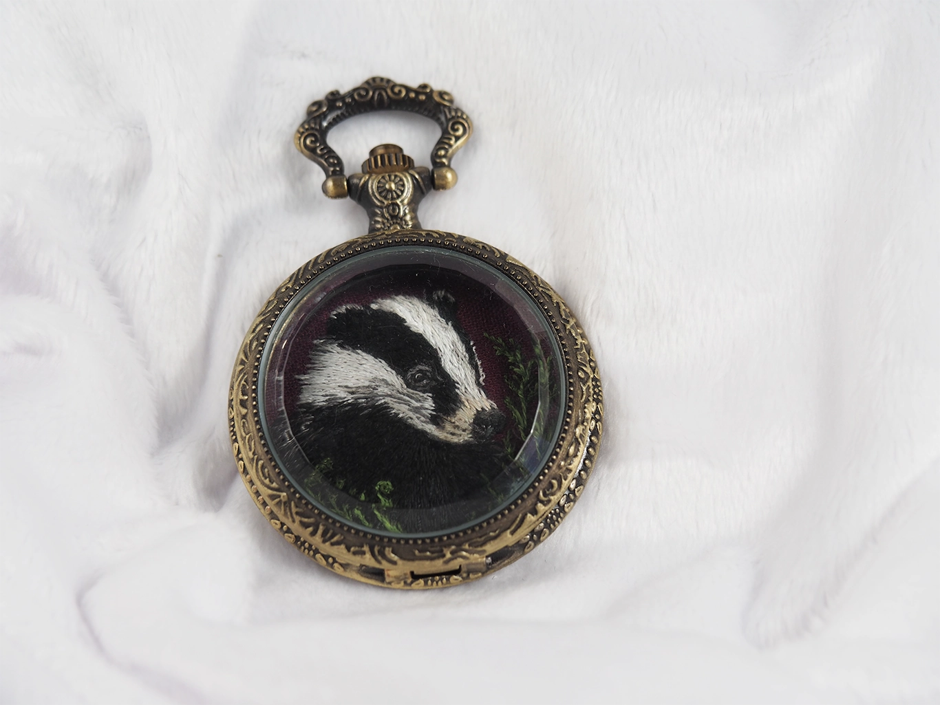 Closed locket casing with badger embroidery hidden inside.