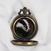 Badger portrait hand-embroidered inside an open locket, front view.