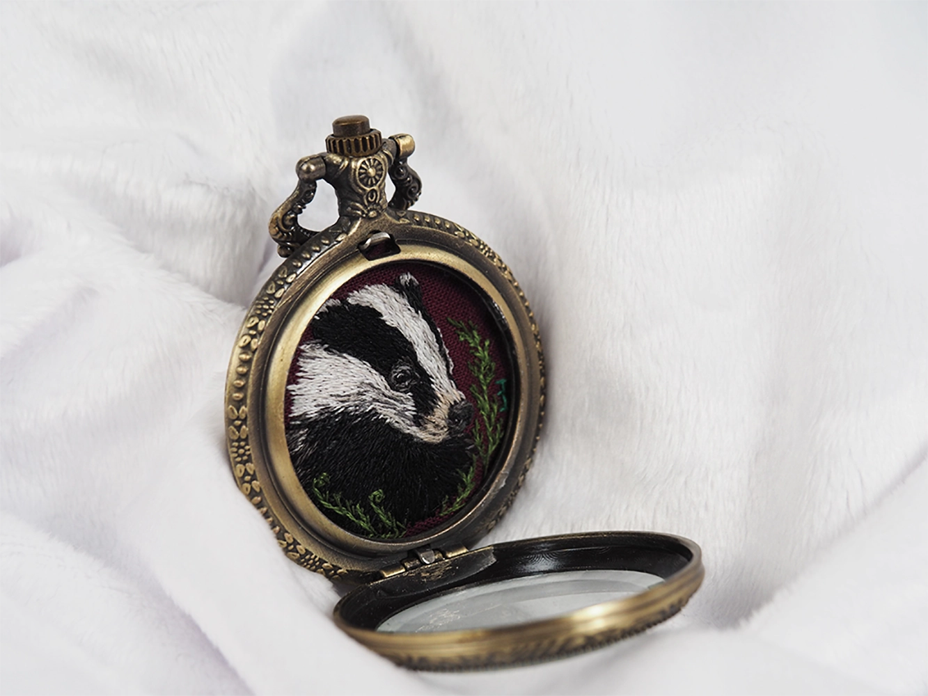 Side view of open locket showing embroidered badger.