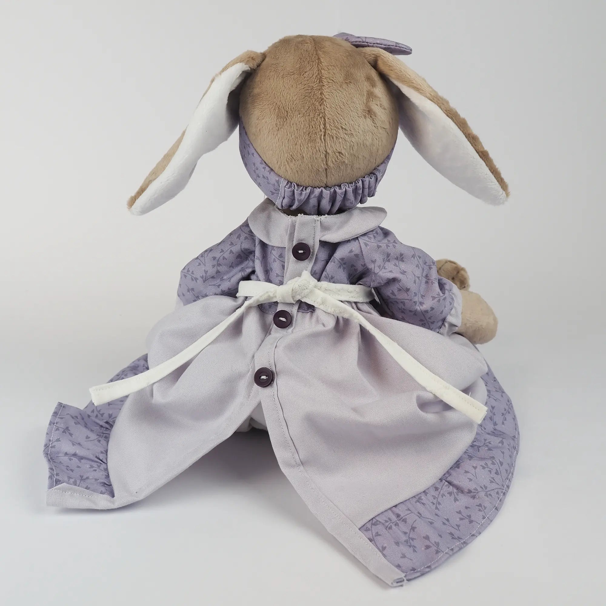 Burrowfolk rabbit, Fern, in her violet dress facing away from camera.  Showing the back detail and button fastening.