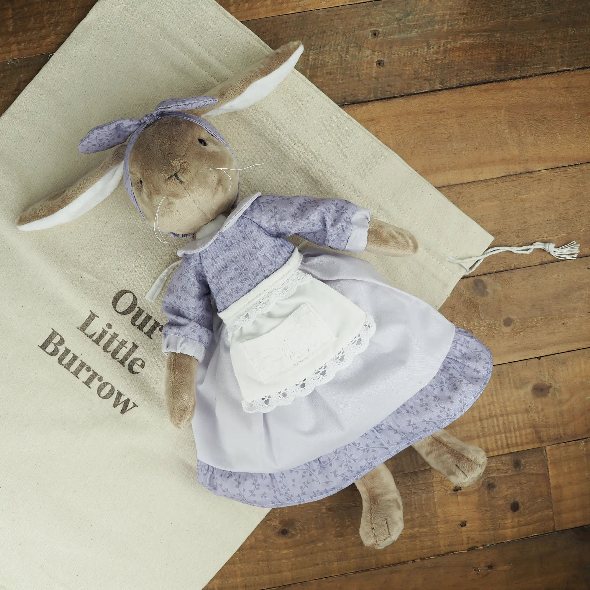 Burrowfolk rabbit, Fern, laying down on an Our Little Burrow branded cloth bag.