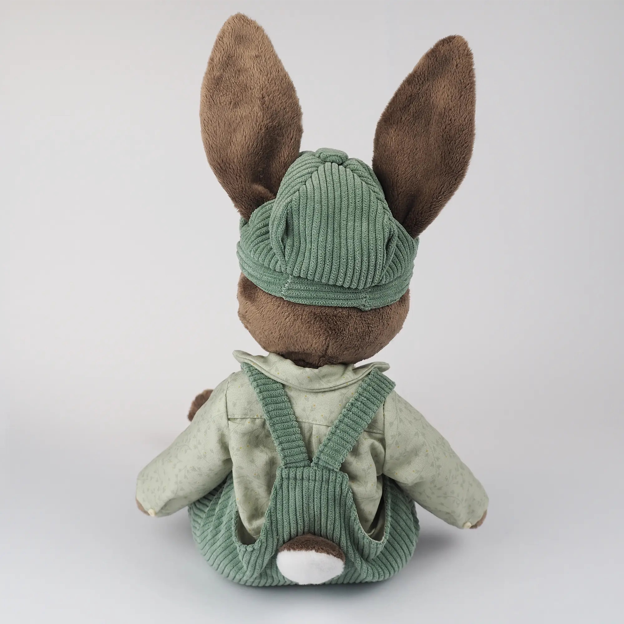 Burrowfolk rabbit, Freddie, sat facing away from the camera.  Showing tail hole detail in his dungarees.