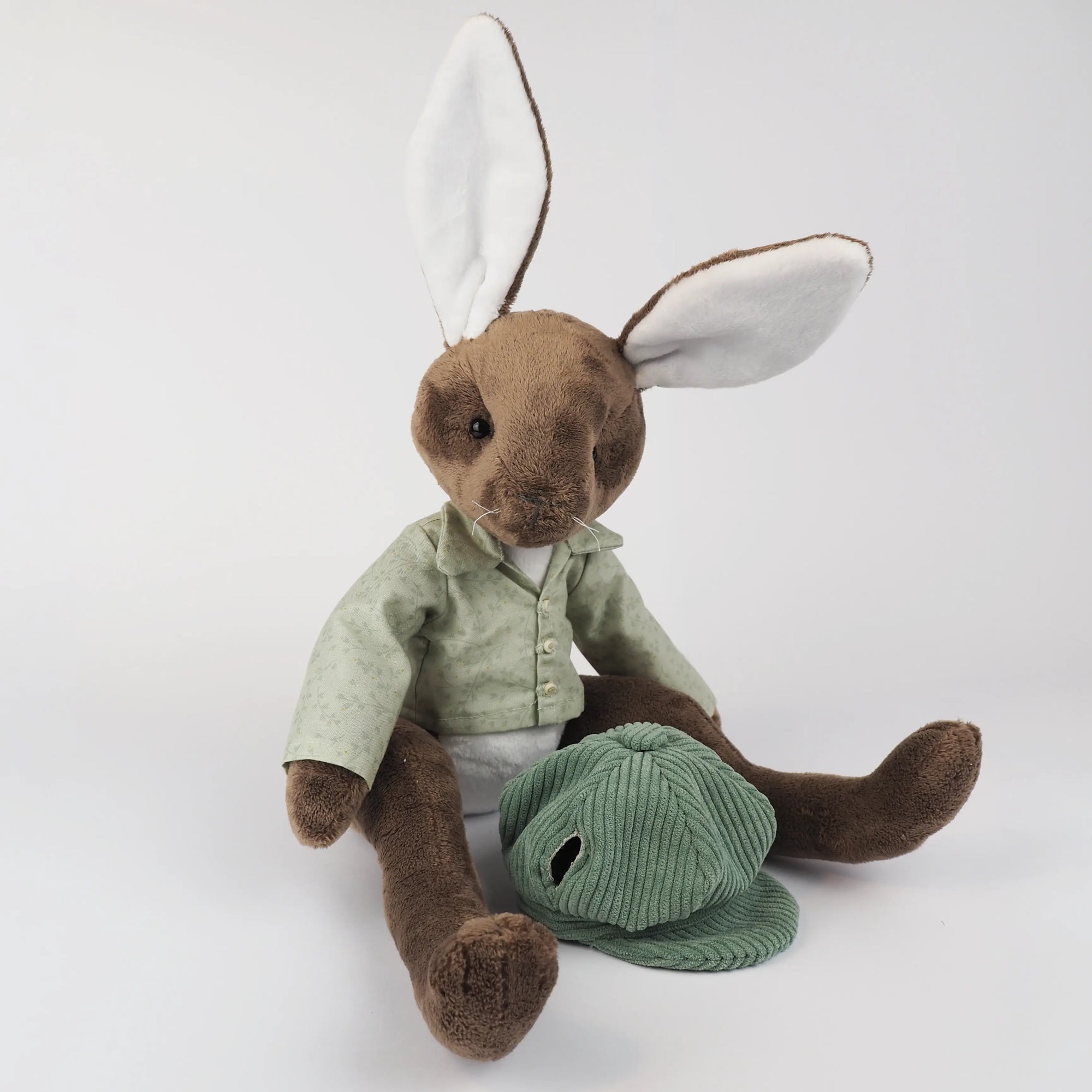 Burrowfolk rabbit, Freddie, sat in just his  green floral shirt and admiring his corduroy hat.