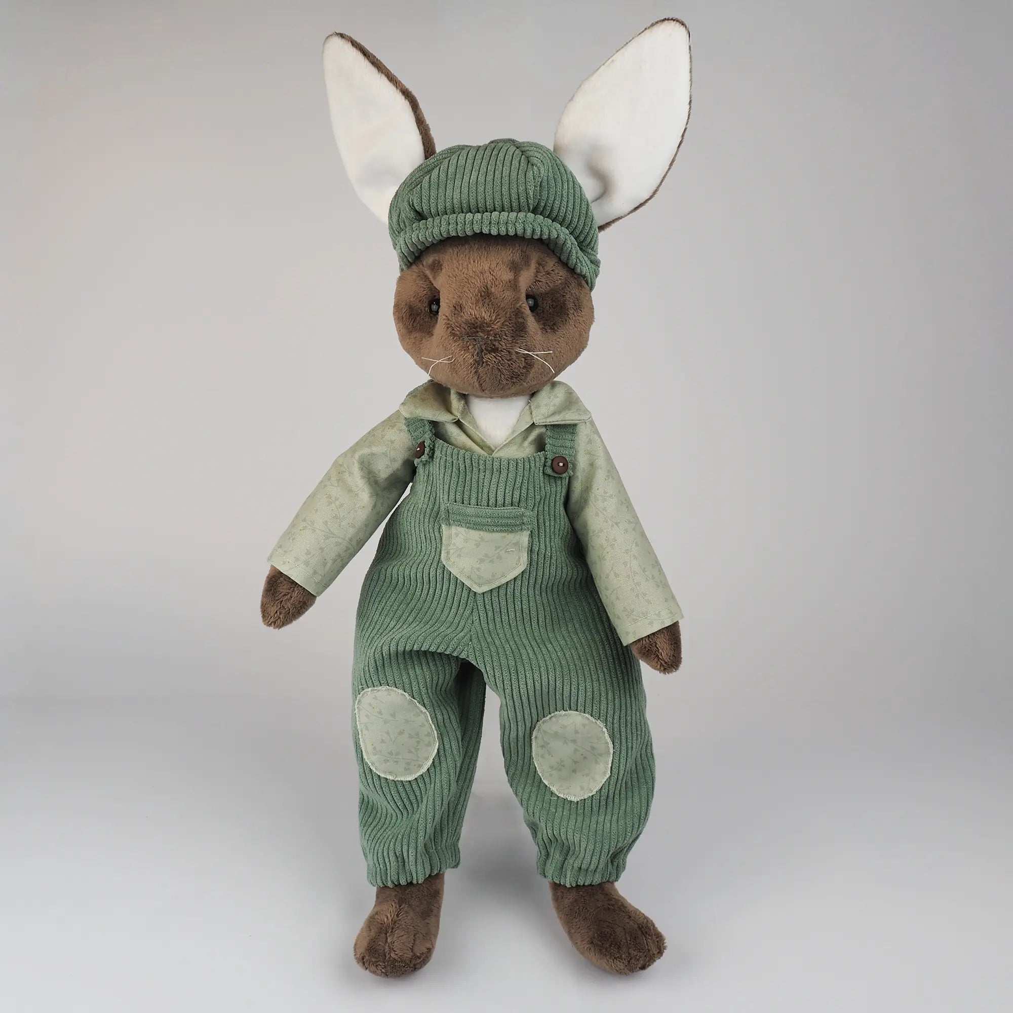 Burrowfolk rabbit, Freddie, standing in his green corduroy dungarees and matching hat.
