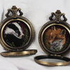 Badger and Fox embroidered lockets displayed side by side, both open.