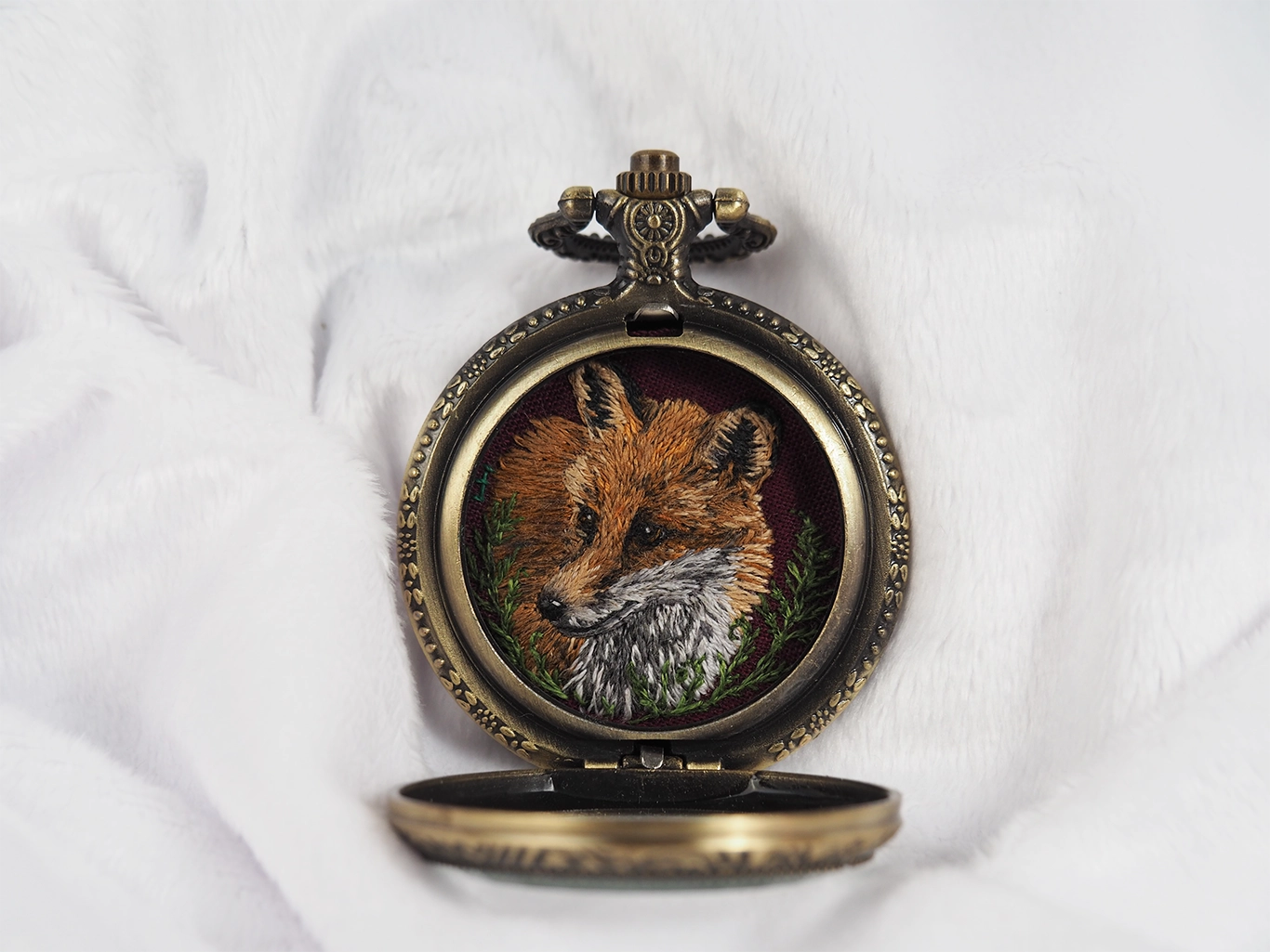 Fox portrait hand-embroidered inside an open locket, front view.