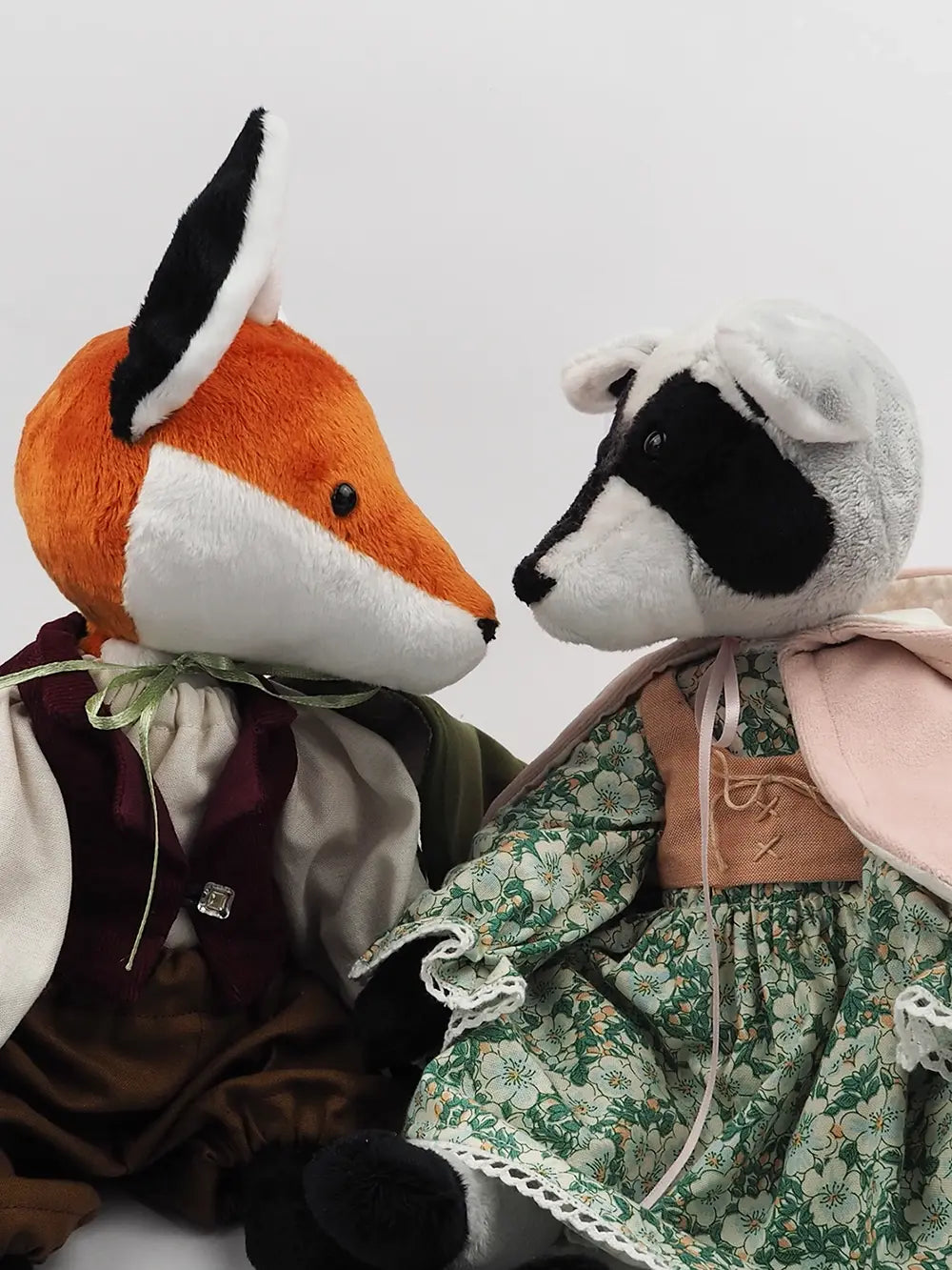 Handmade plush companions Mr Whiskers the fox and Pouches the raccoon gazing at each other